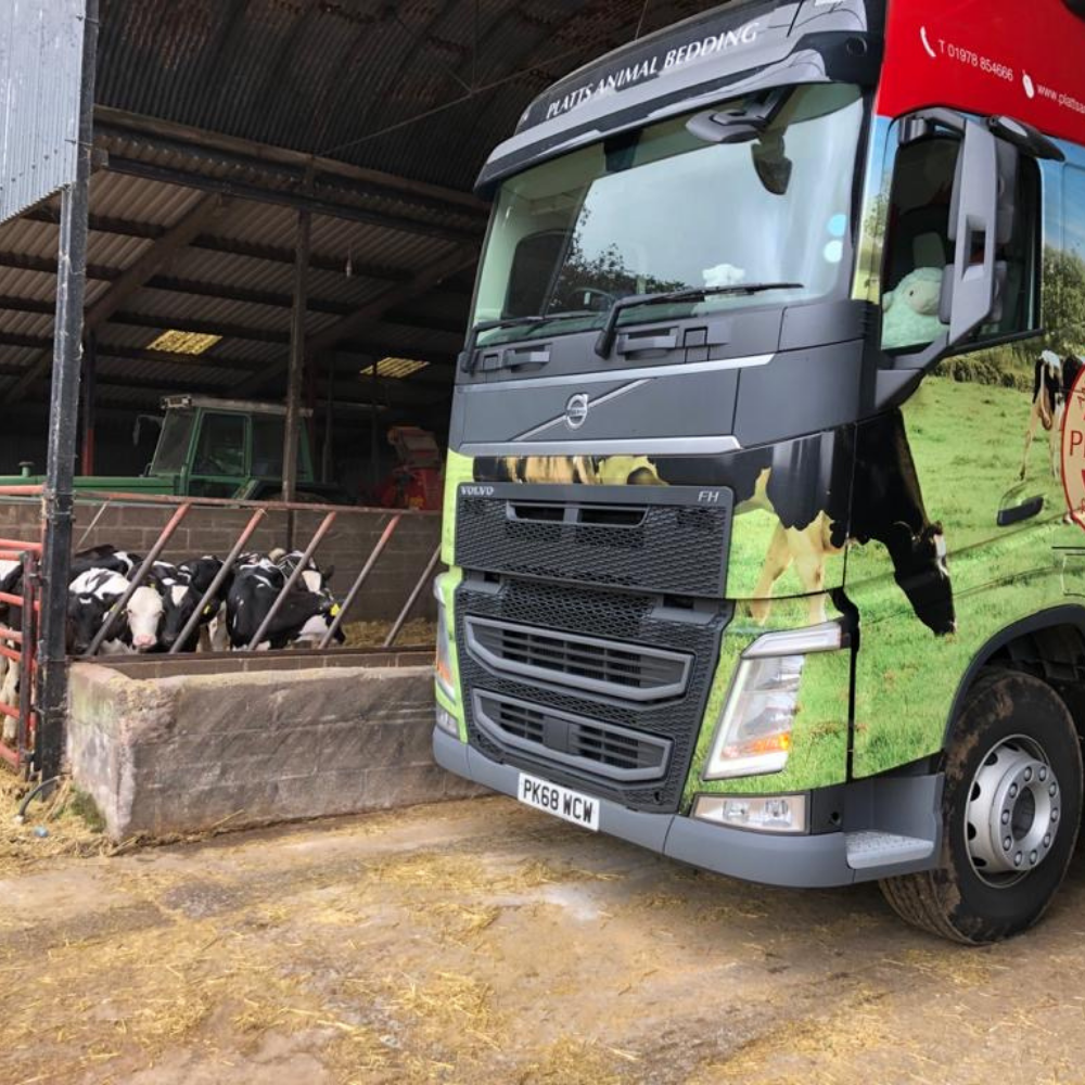 Platts animal bedding delivery vehicle at an agricultural building.